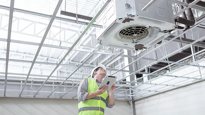 Hombre con equipo de seguridad inspecciona un ventilador industrial.