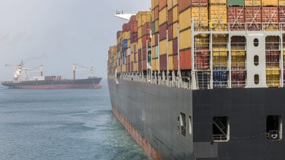 Gran buque portacontenedores cargado con contenedores coloridos navega junto a otro barco en el mar abierto